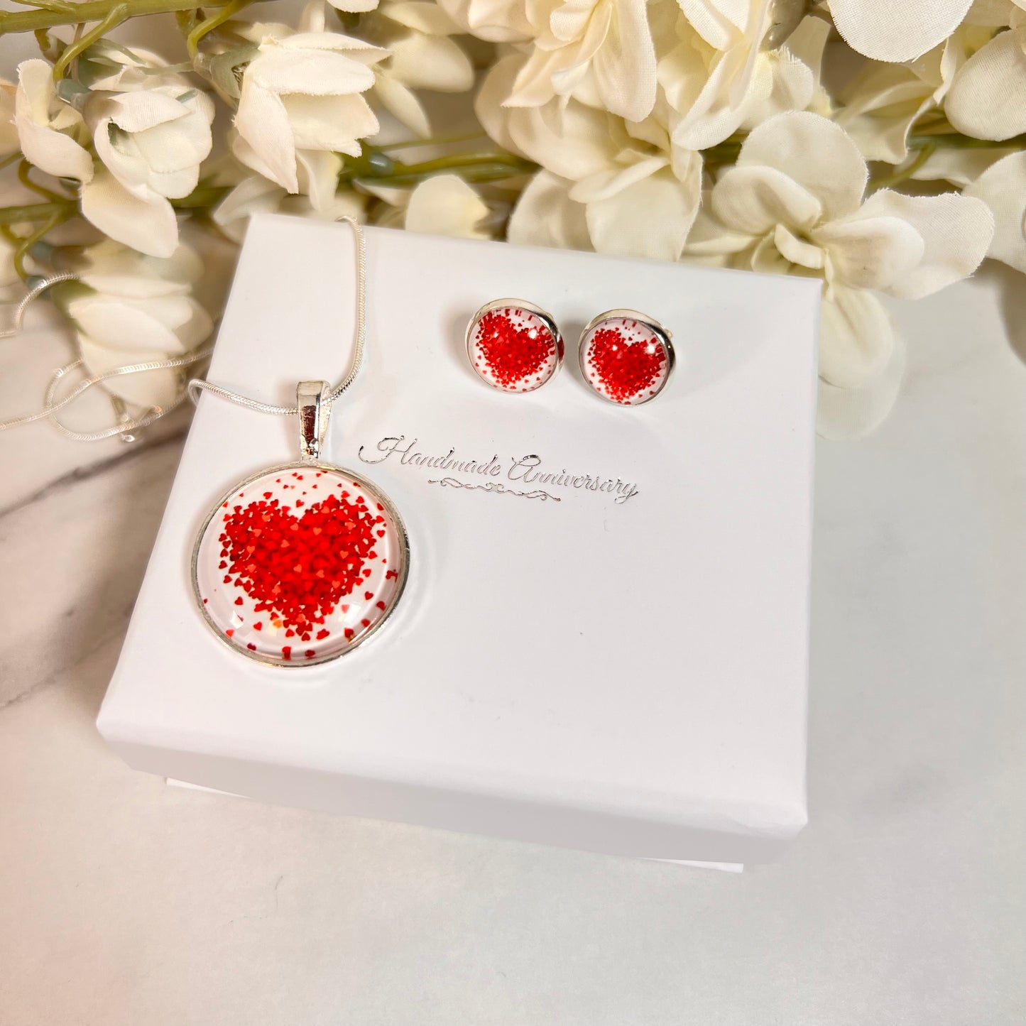 Valentine heart pendant and earring set with their box and flowers in the background