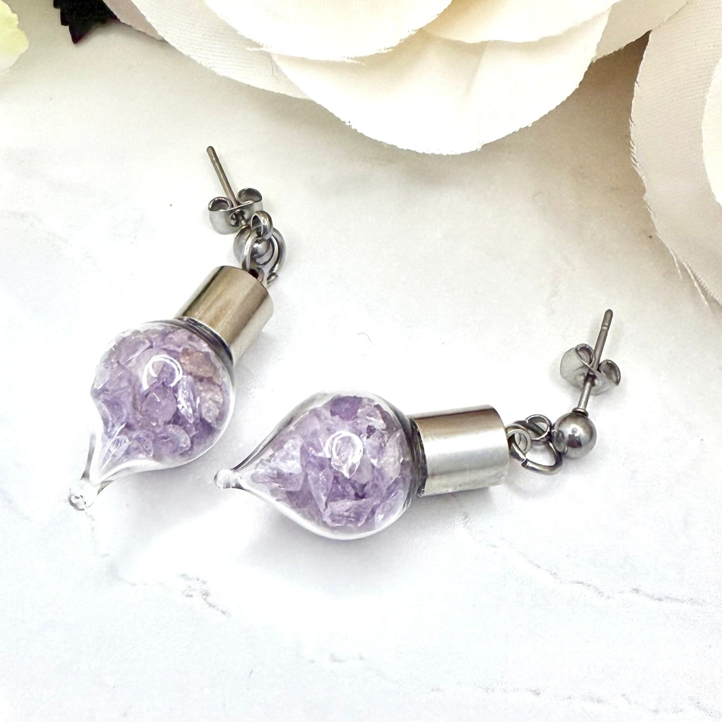 close up of amethyst wedding anniversary earrings showing stud details and glass vials filled with natural amethyst