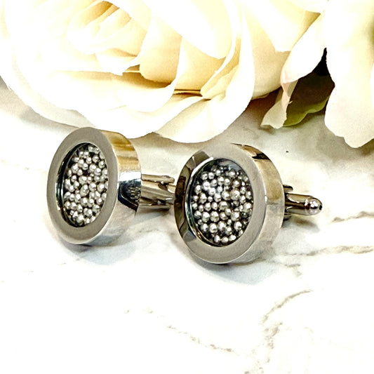 close up of side view of large stainless steel cufflinks filled with balls of shiny pure tin