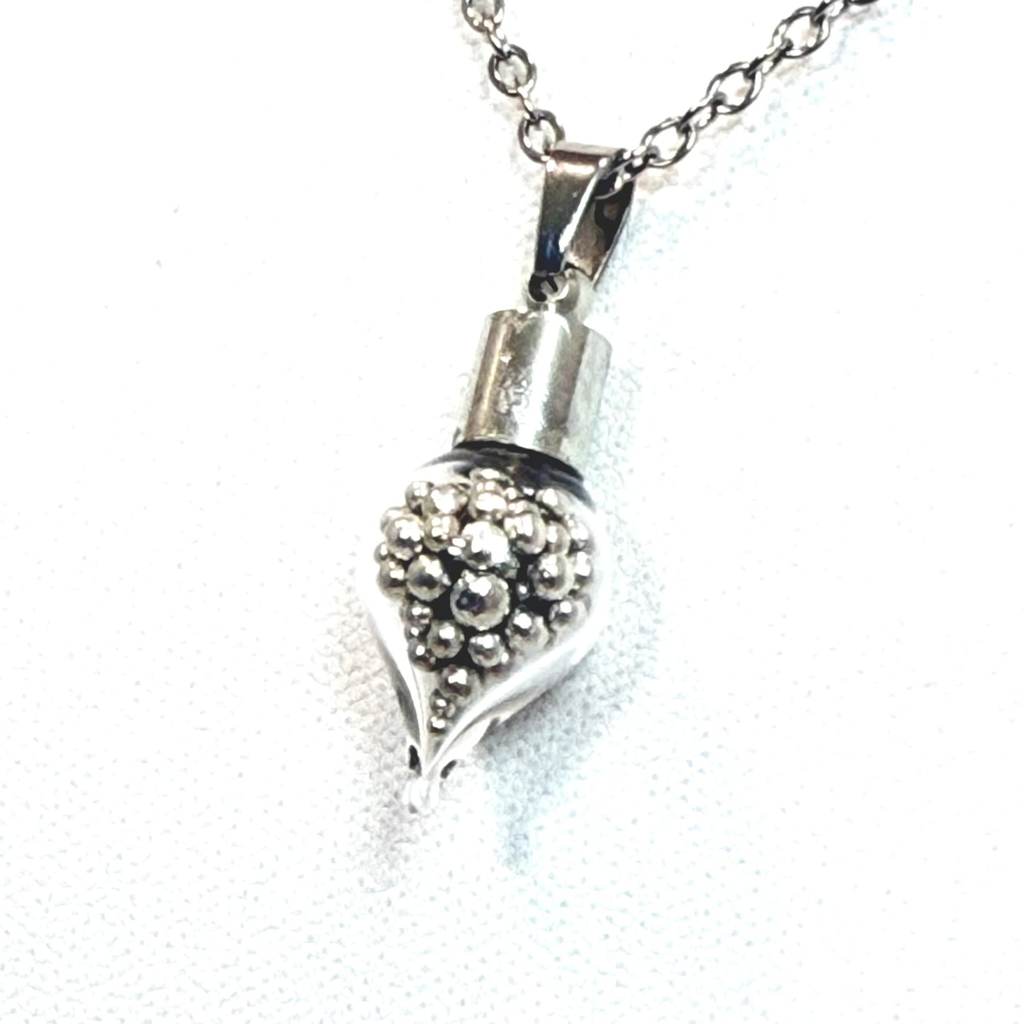 close up of teardrop shaped glass pendant filled with balls of pure tin