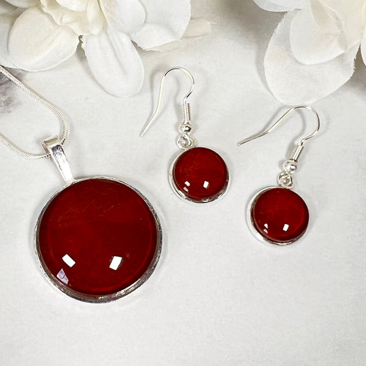a picture showing a round leather pendant and a pair of leather drop earrings in silver settings