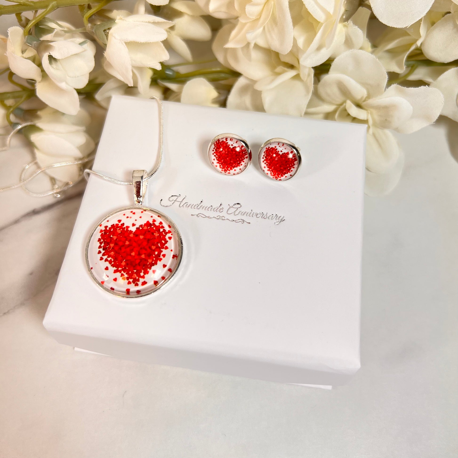 Valentine heart pendant and earring set with their box and flowers in the background