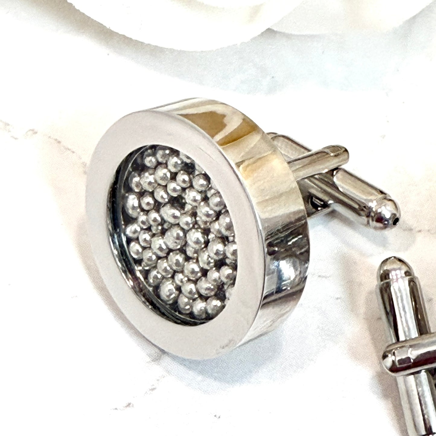 close of a single cufflink showing details of cufflinks filled with pure tin