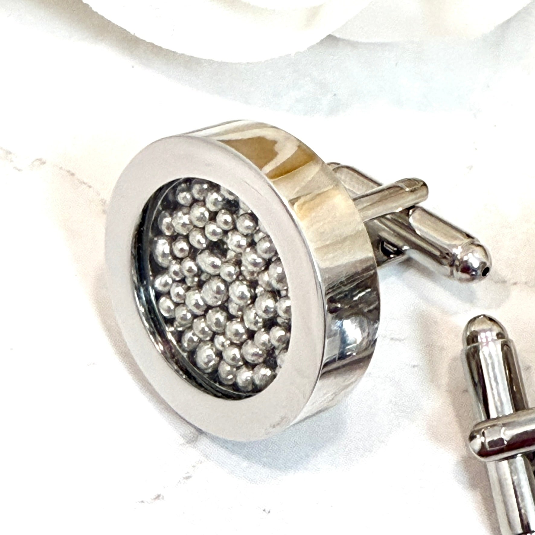 close of a single cufflink showing details of cufflinks filled with pure tin