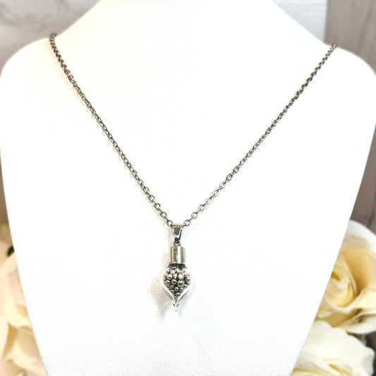 Glass pendant on necklace filled with shiny pure tine balls on a stand